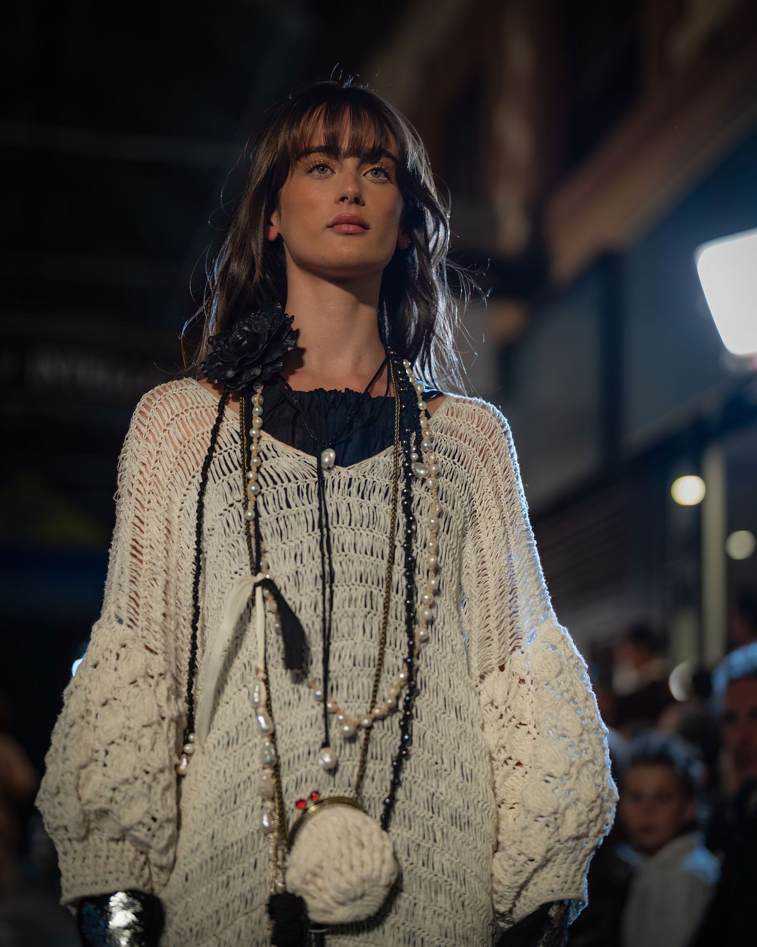 A person wearing a cream-colored knit sweater and black bow tie poses in a series of artistic fashion photographs.