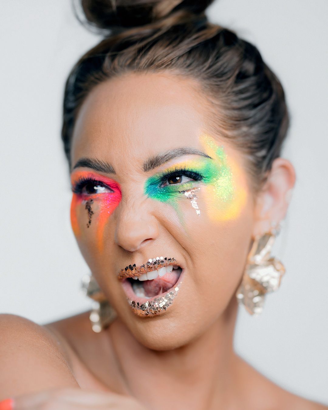 Creative beauty portrait with colorful glitter makeup, crystal lips, and statement earrings.