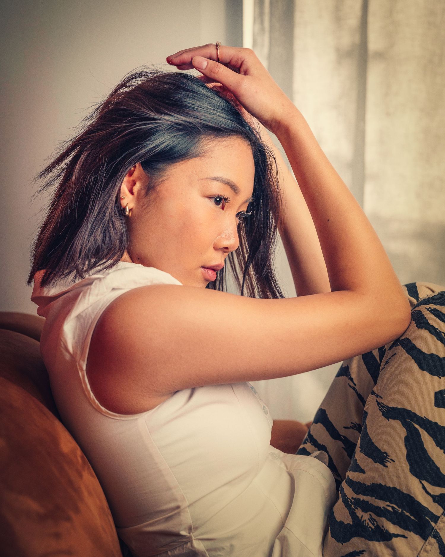 Moody boudoir photoshoot on leather sofa in natural light setting.