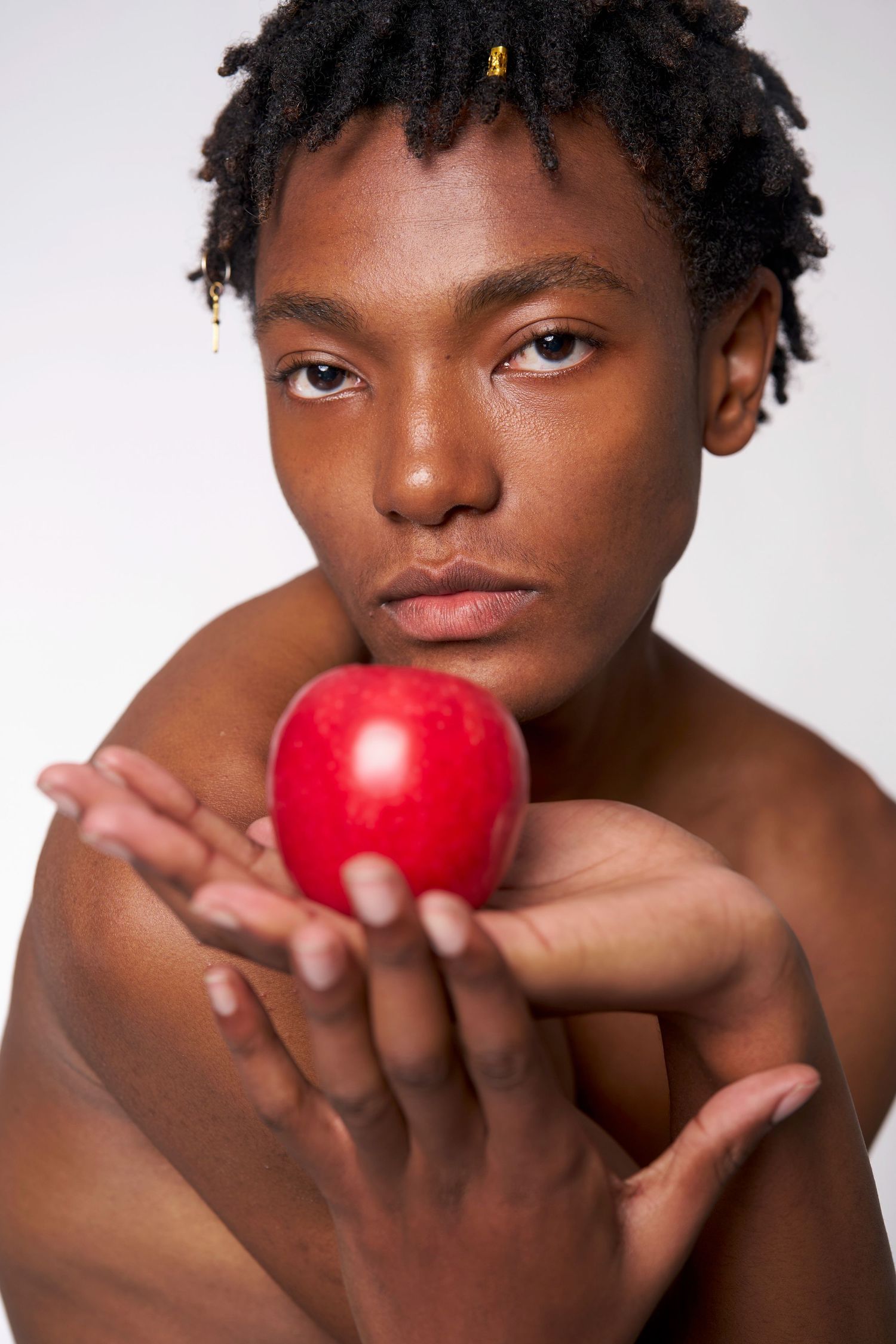 A series of artistic portraits showing a person holding and posing with a bright red apple against a white background.
