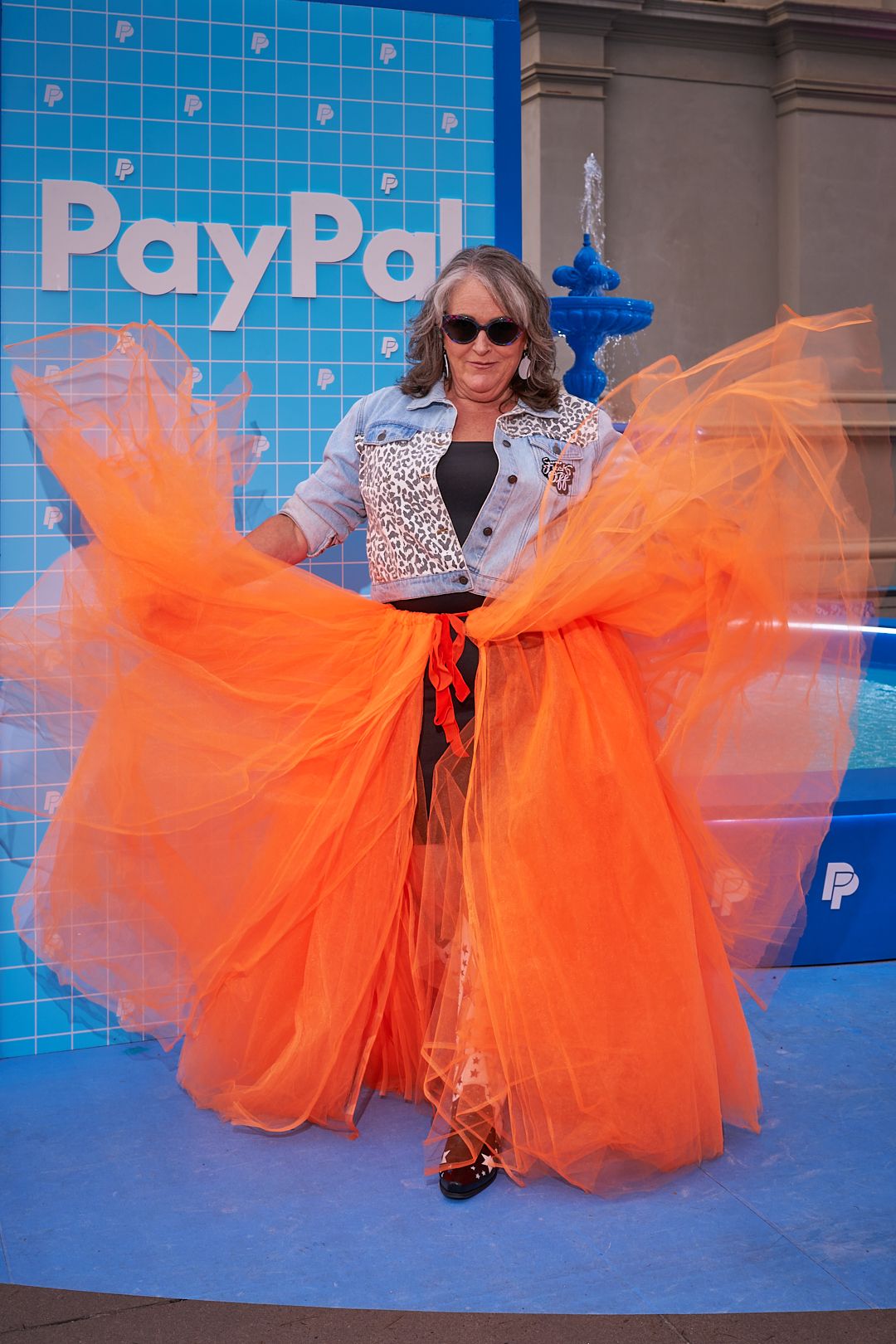 A dynamic sequence shows a bright orange tulle dress flowing and twirling against a blue backdrop with PayPal branding.