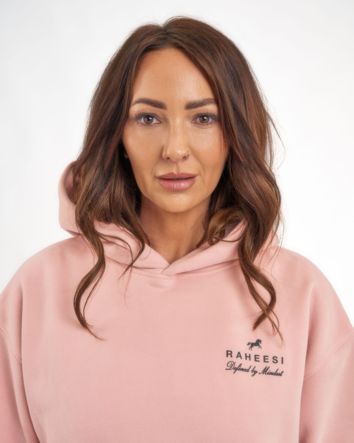 Close-up of woman in a pink Raheesi Defined by Mindset pullover hoodie.