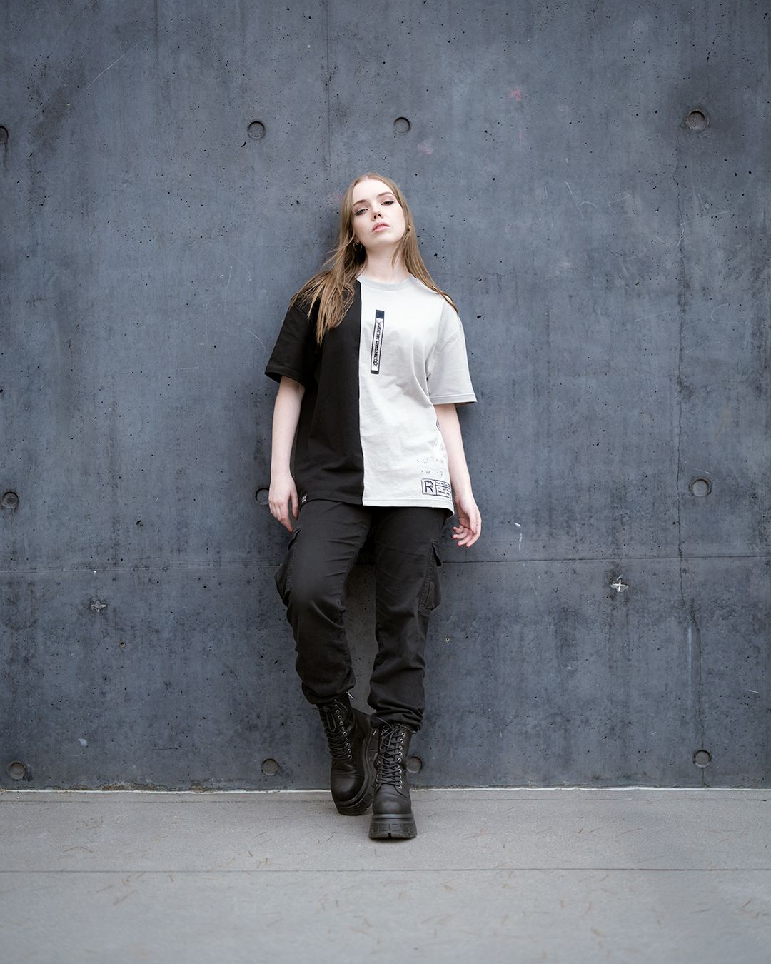 Full body fashion portrait in urban setting wearing contrast split t-shirt and combat boots.