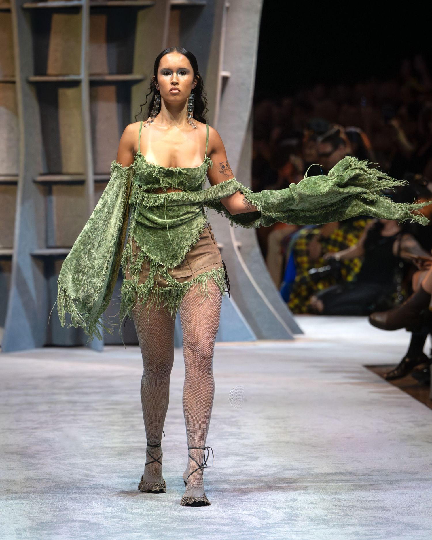Models walk runway in avant-garde green leaf-inspired fashion designs during fashion show presentation.