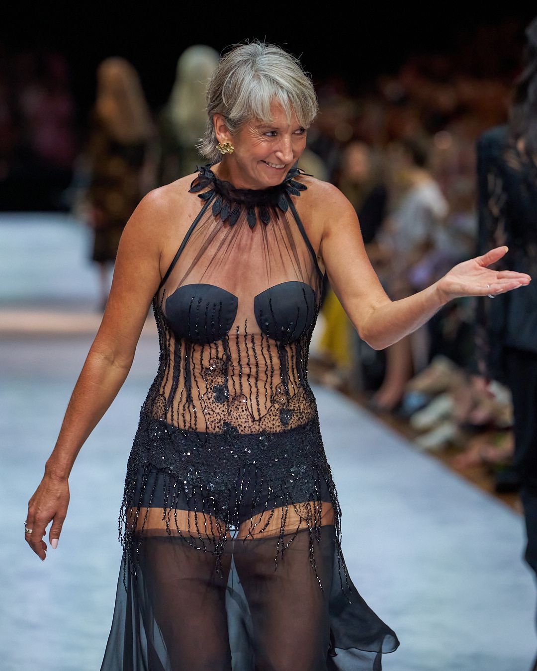 A model walks the runway in a sheer black lace lingerie ensemble during a fashion show.