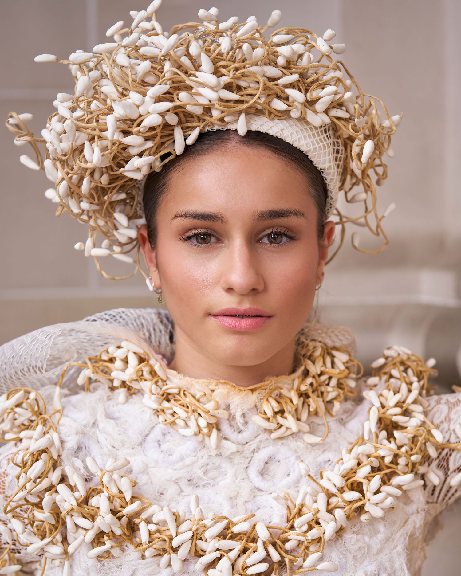 Fashion portrait featuring delicate white lace and golden paper flower crown creating an ethereal artistic composition.