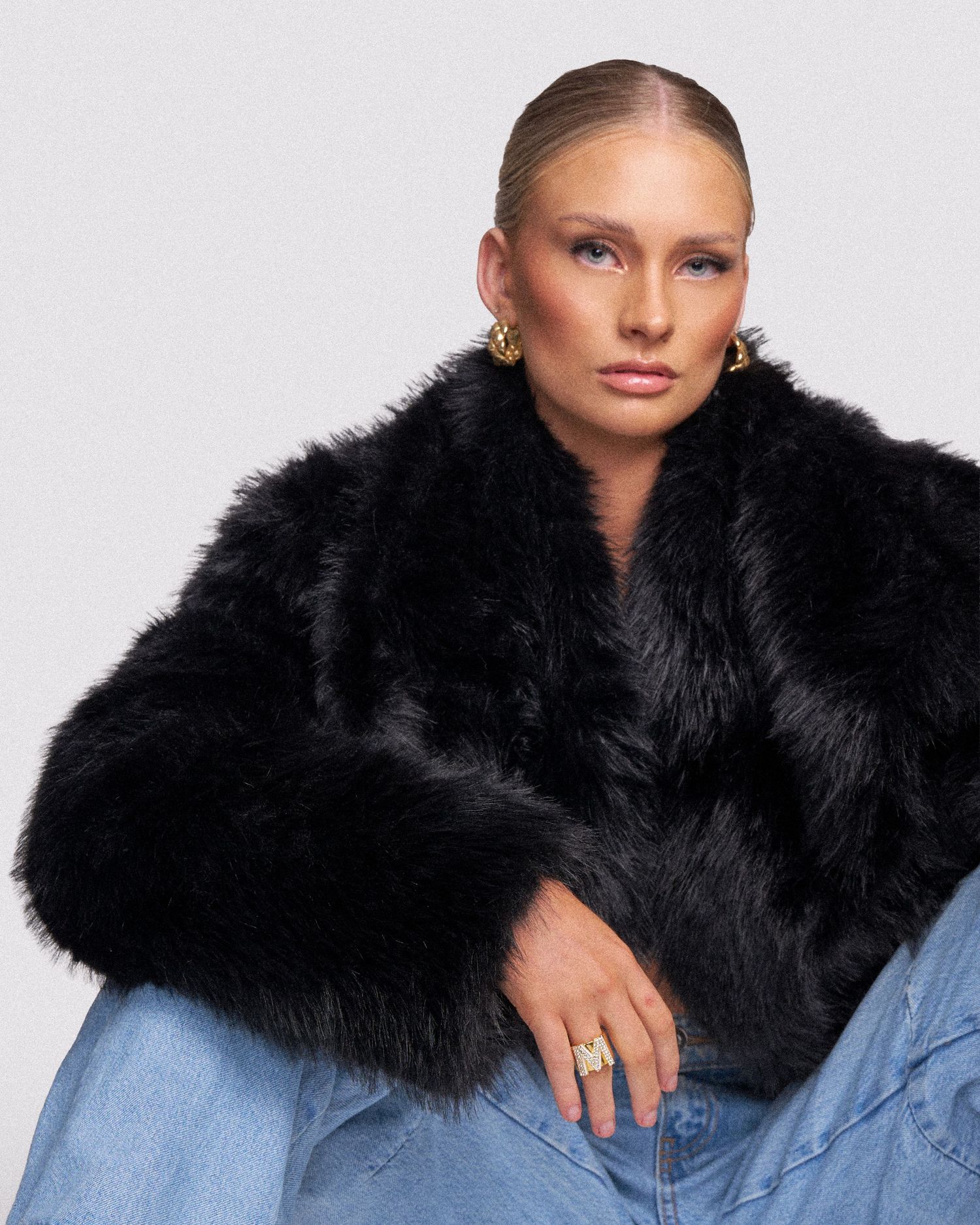 Model wearing a black fur collar jacket with denim in a fashion portrait series.