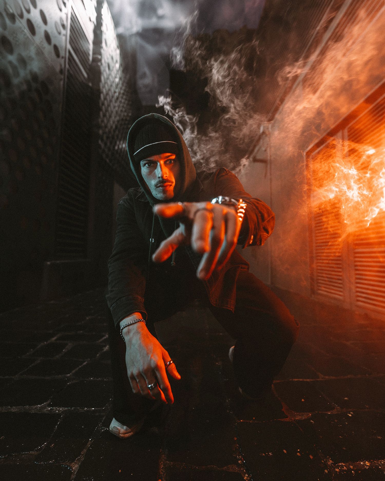 Moody street photography with smoke and orange lighting effects in urban alley.