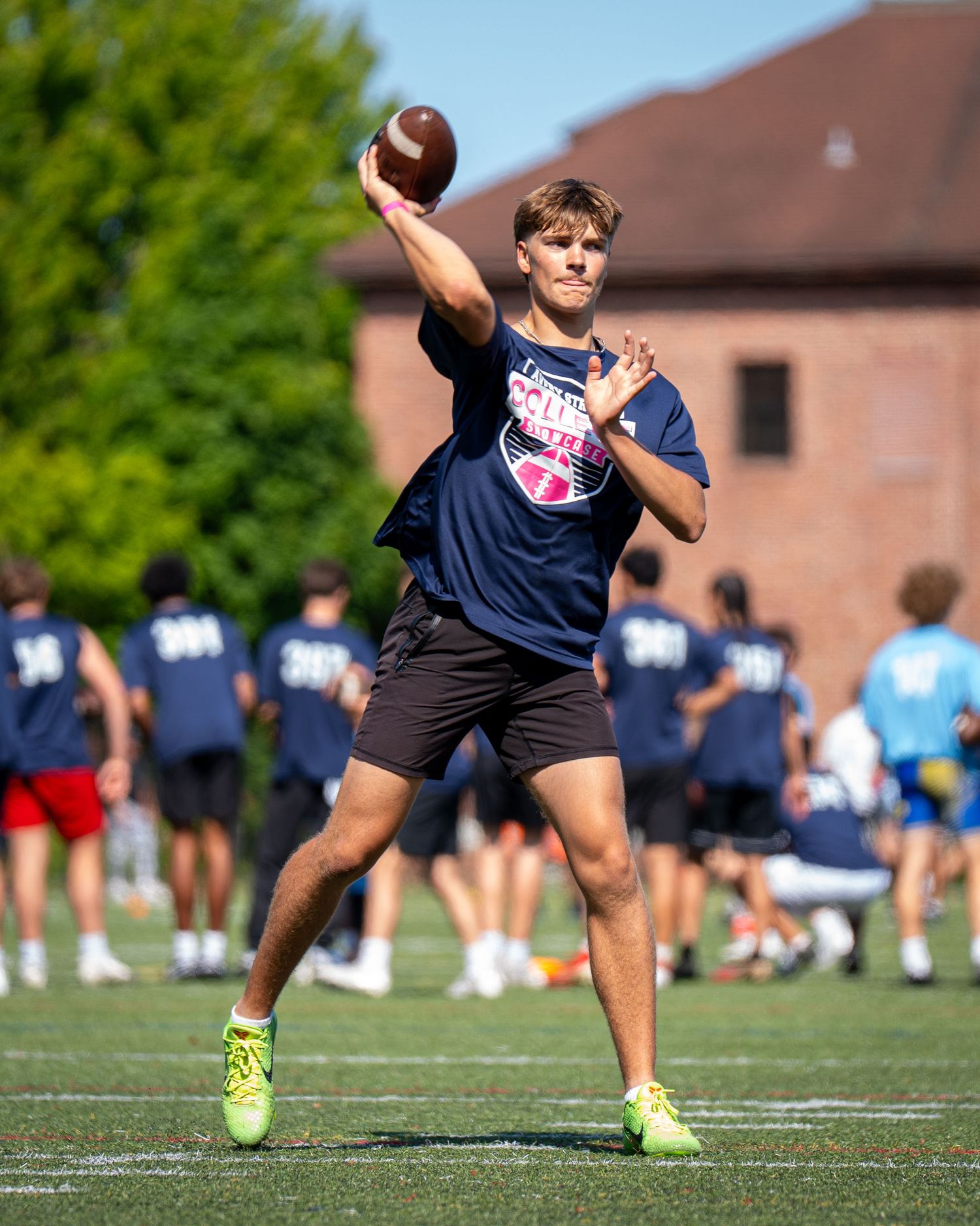 Young quarterback throwing a football during an outdoor football camp practice on a green turf field.