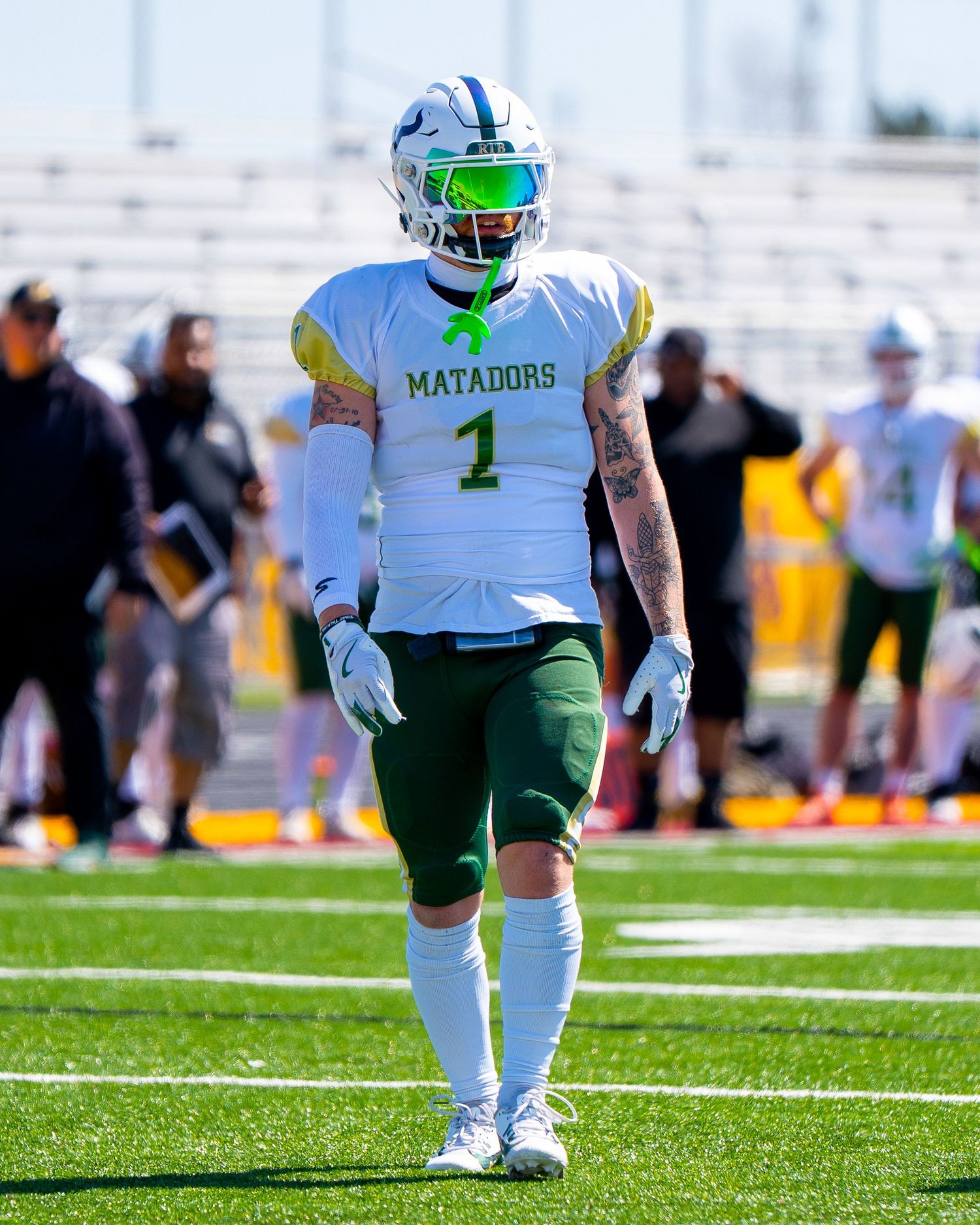 Football player in white Matadors uniform with number 1 stands on field during game.