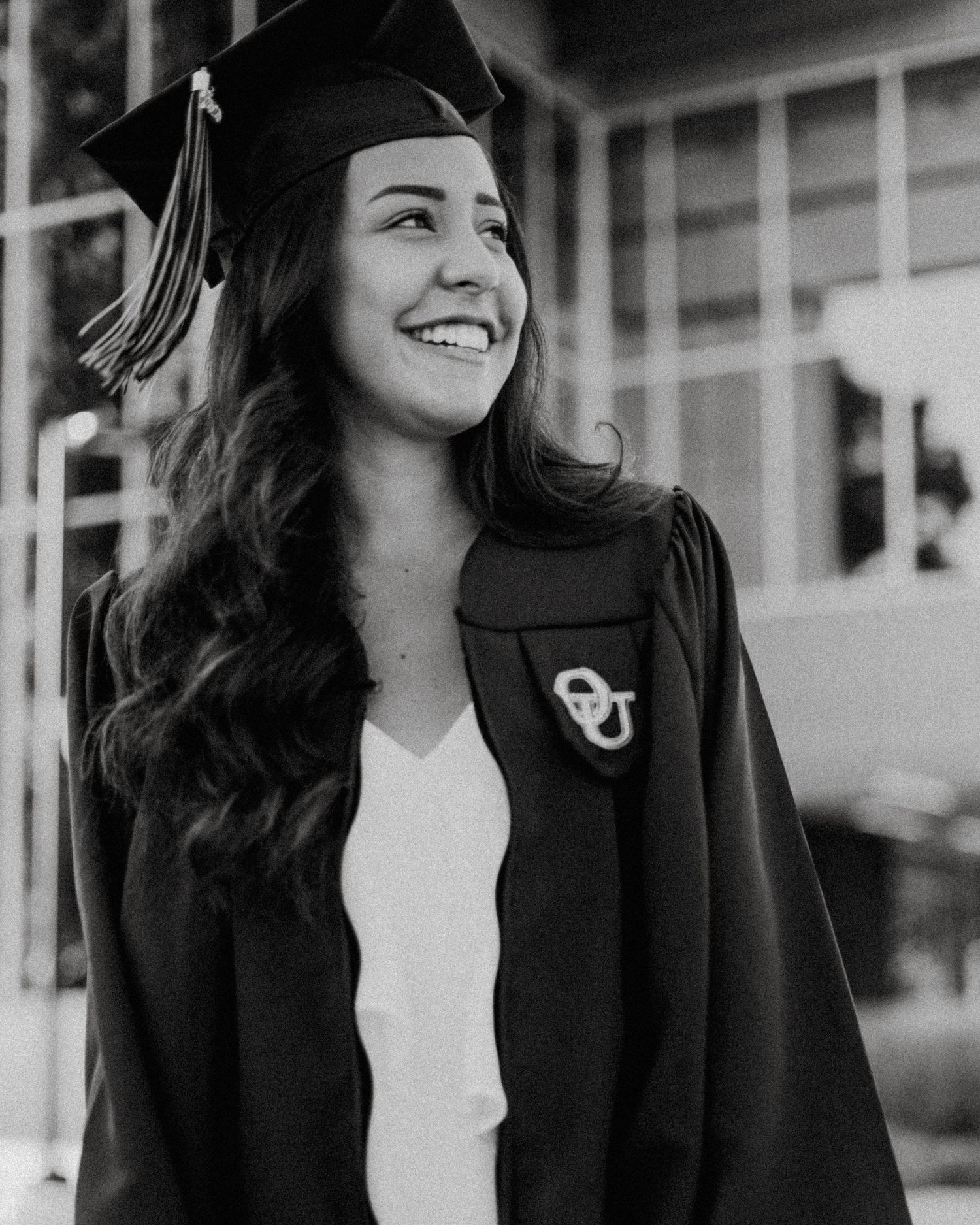 Black and white graduation portrait of smiling woman near campus by Bylitos Studio Michigan