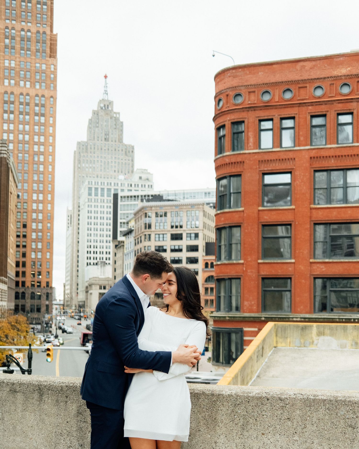 Engagement couple on rooftop with Detroit skyline in the background by Bylitos Studio Michigan