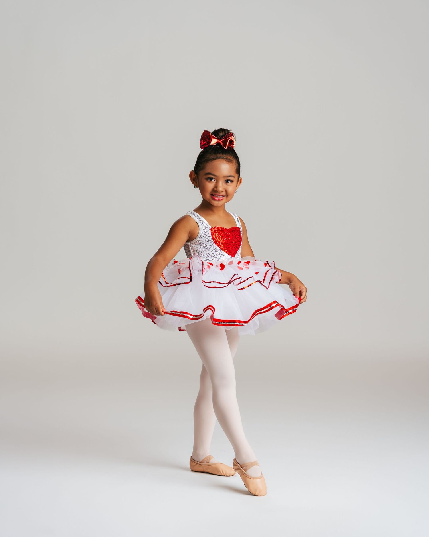 Young ballerina in red and white tutu smiling during dance recital portrait by Bylitos Studio Michigan