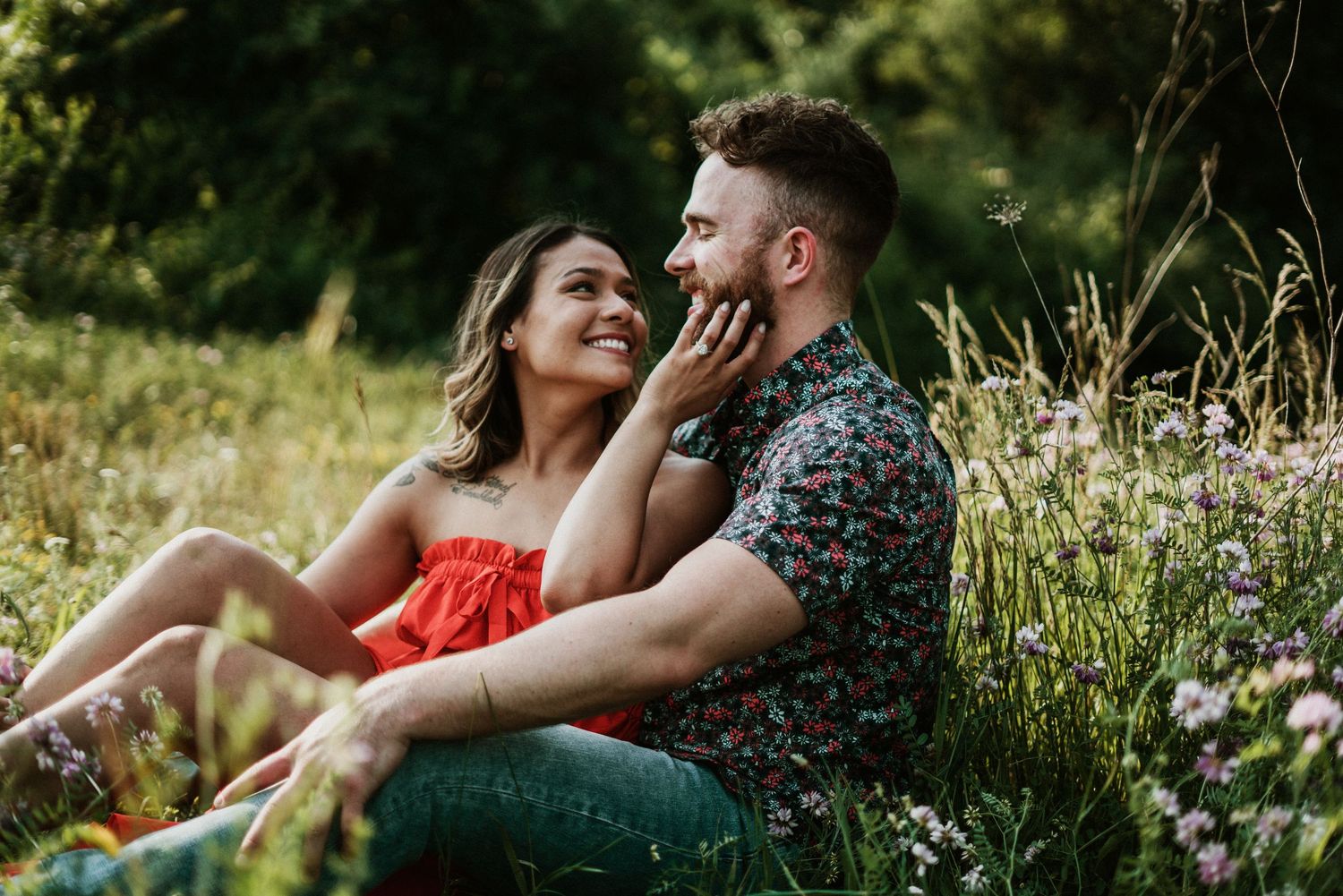 Couple sitting together in a wildflower meadow during engagement session by Bylitos Studio Michigan