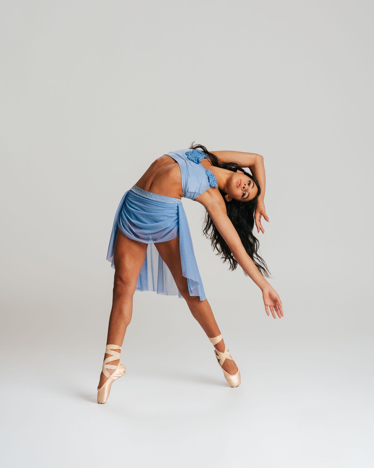 Dancer in floral leotard tucked in a squat pose during studio editorial session by Bylitos Studio Michigan