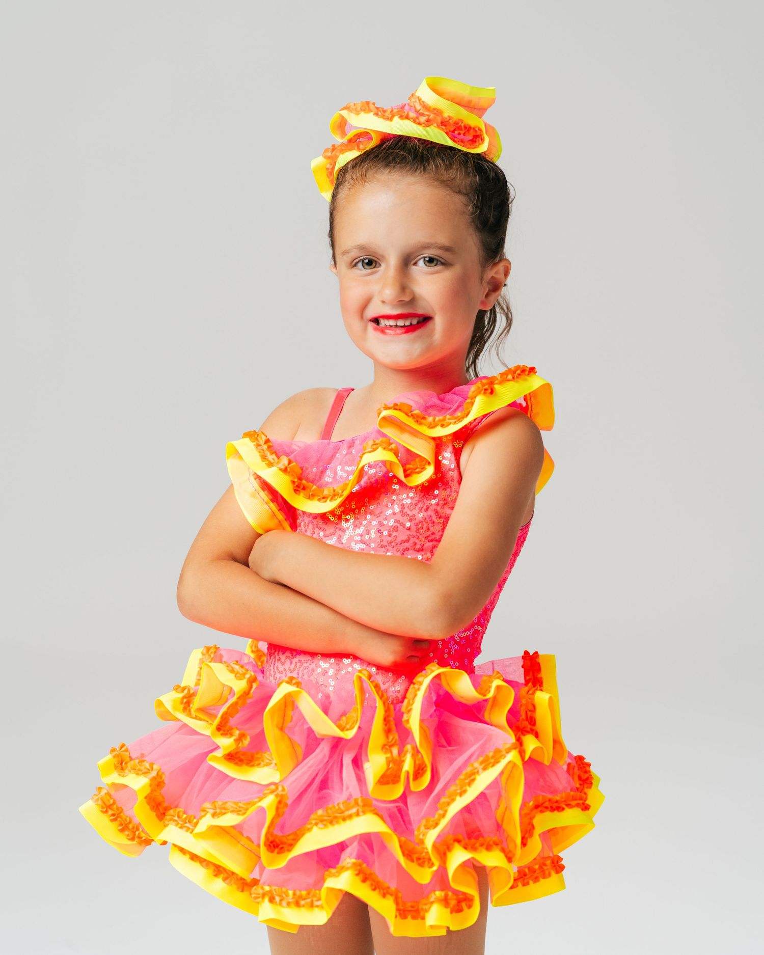 Young dancer in colorful orange ruffled dress during studio editorial shoot by Bylitos Studio Michigan