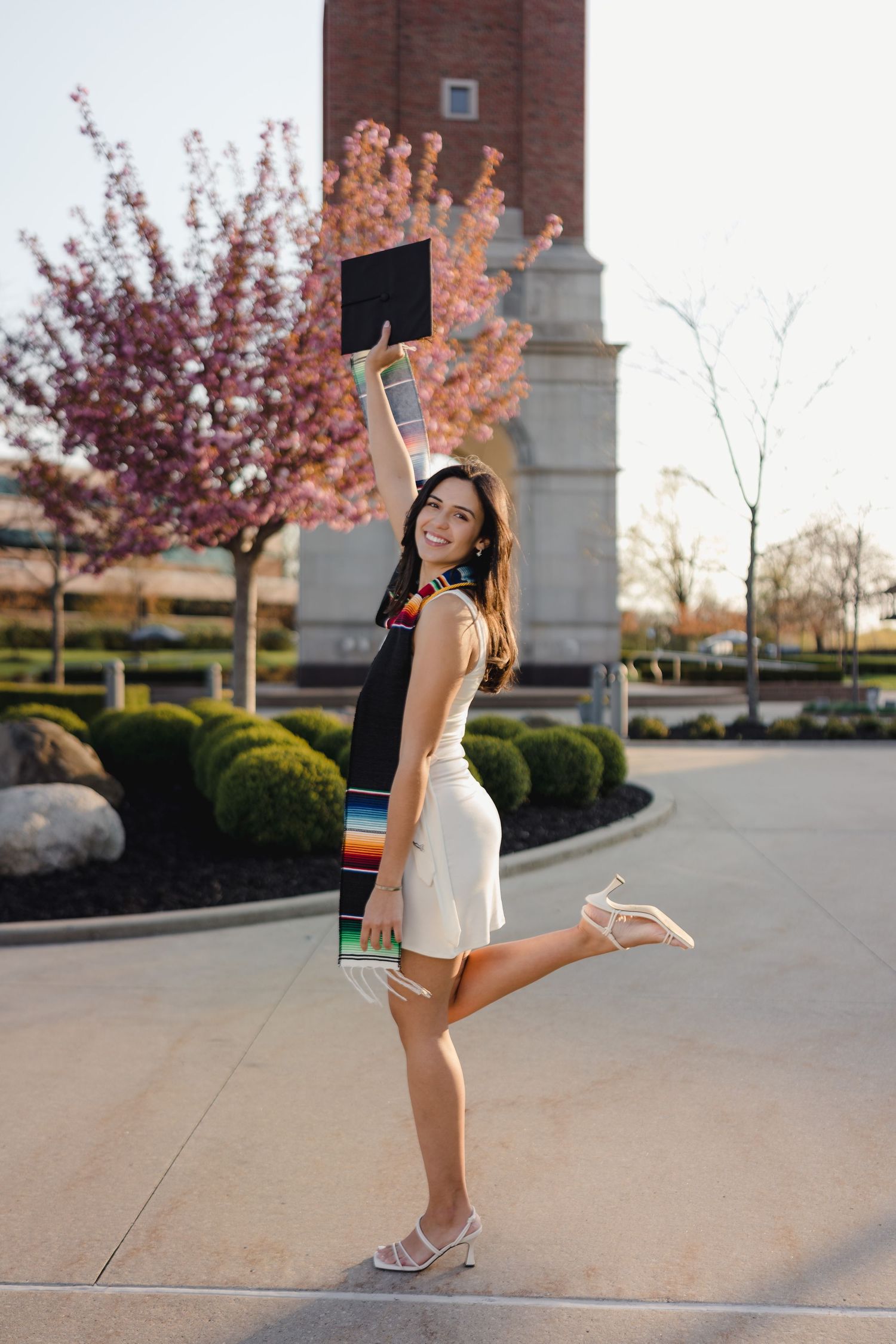 Graduate celebrating by tossing cap near a Michigan university campus by Bylitos Studio Michigan