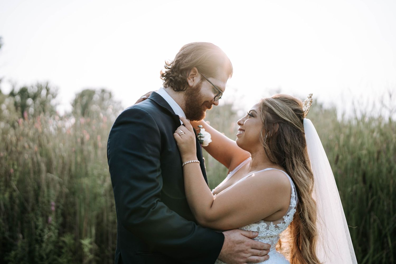Bride and groom sharing a laugh in golden hour sunlight in a meadow by Bylitos Studio Michigan