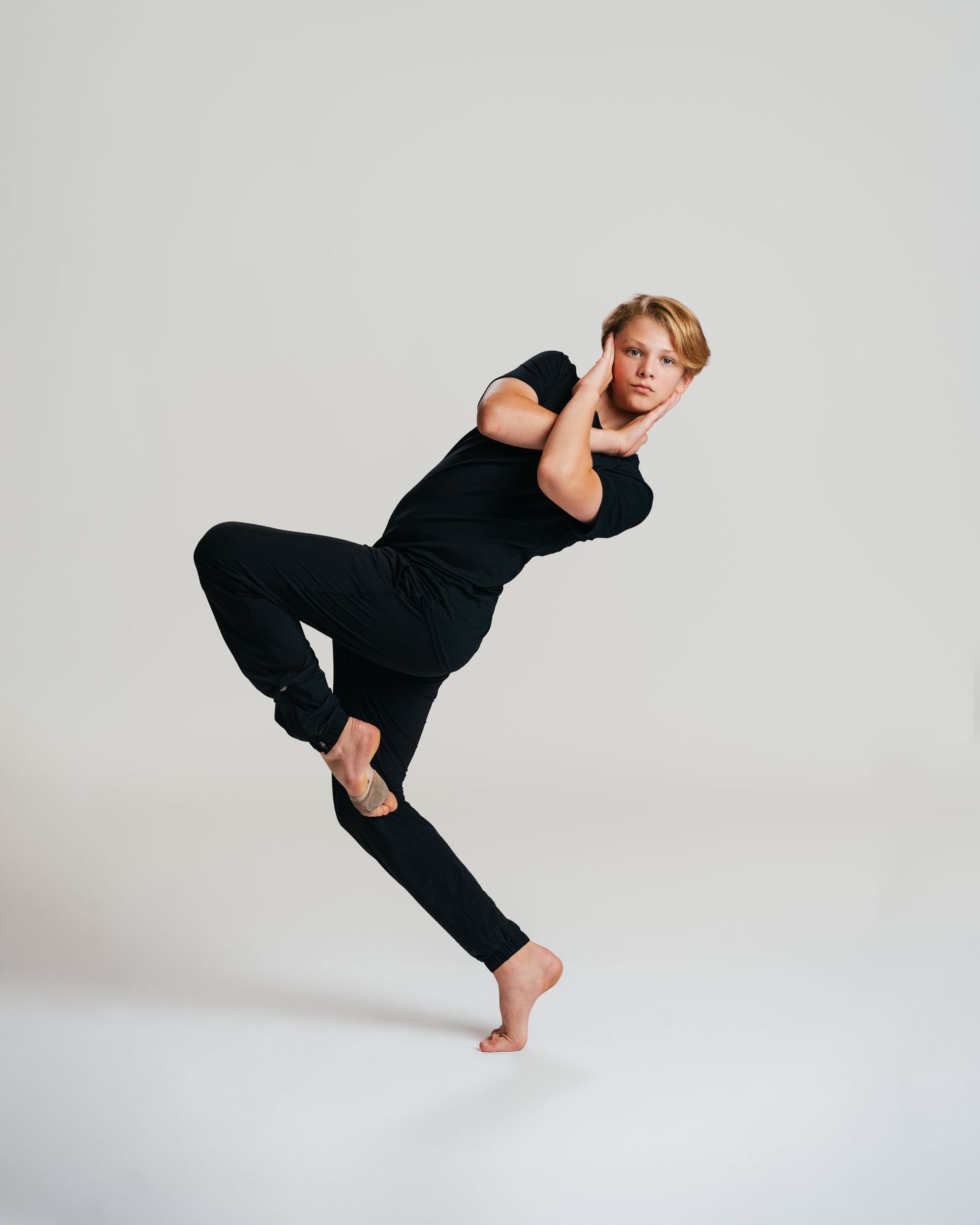Male dancer all in black mid-jump during studio dance editorial session by Bylitos Studio Michigan