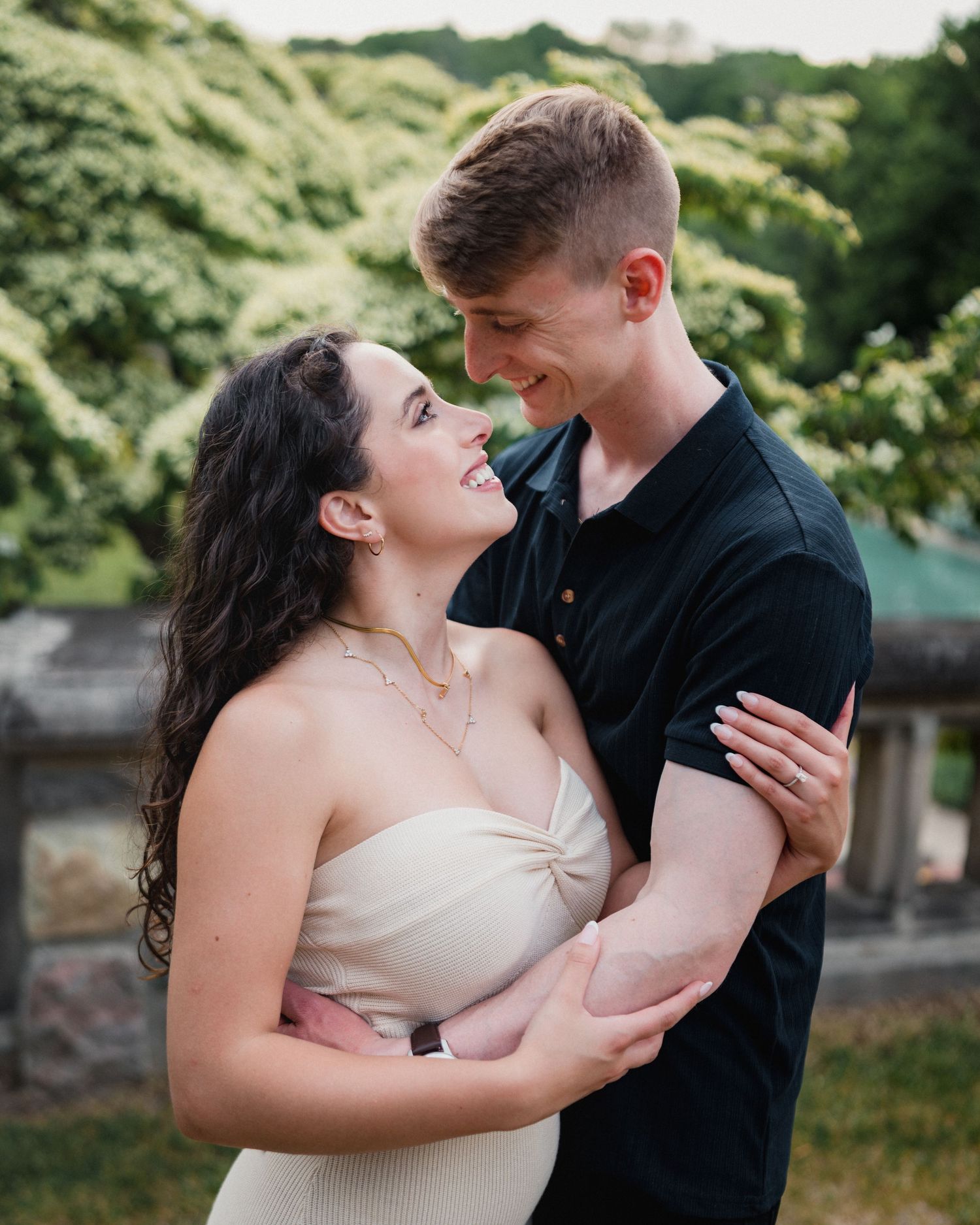 Couple gazing at each other in a lush garden during engagement session by Bylitos Studio Michigan