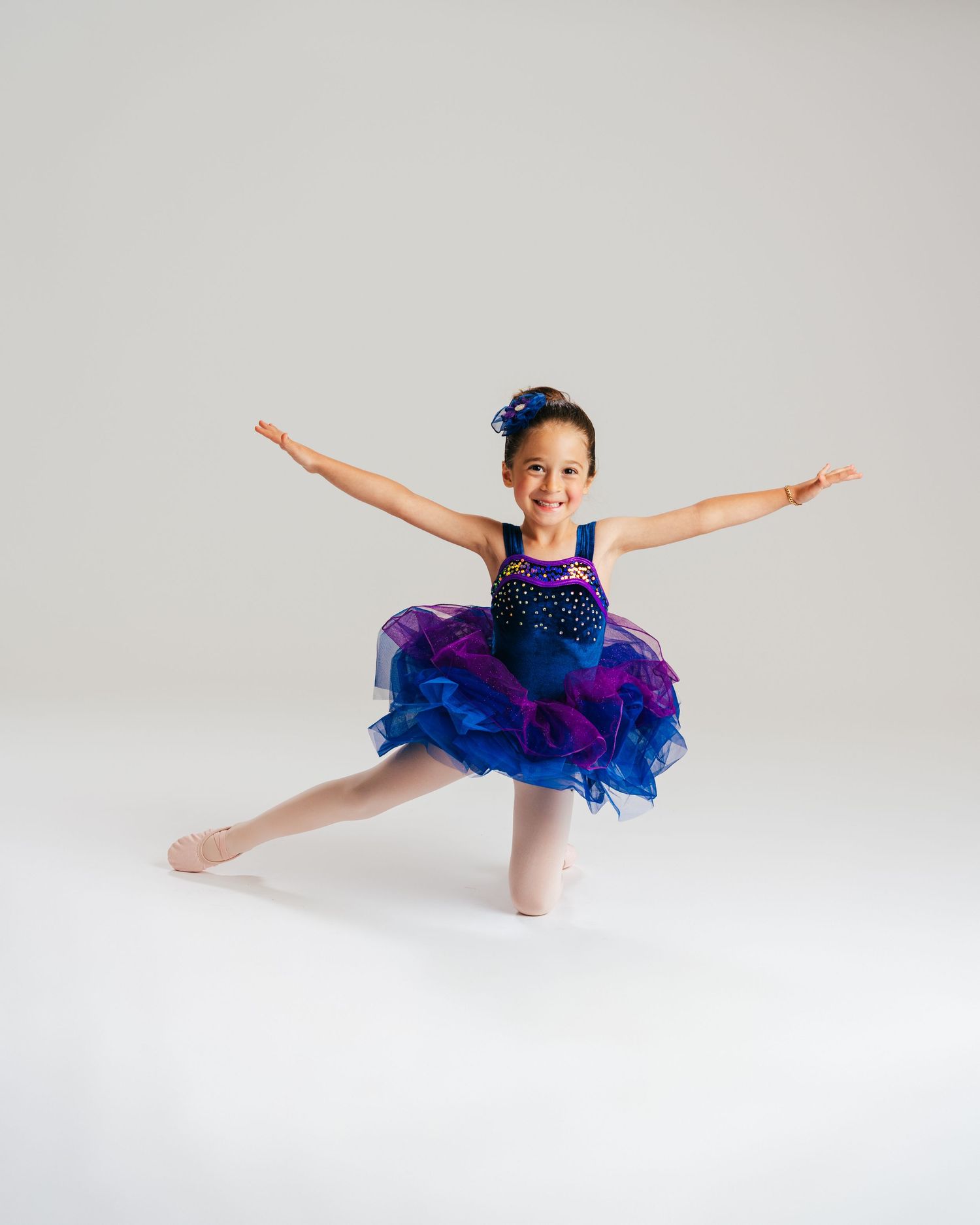 Young dancer in blue tutu with arms wide during dance studio portrait by Bylitos Studio Michigan