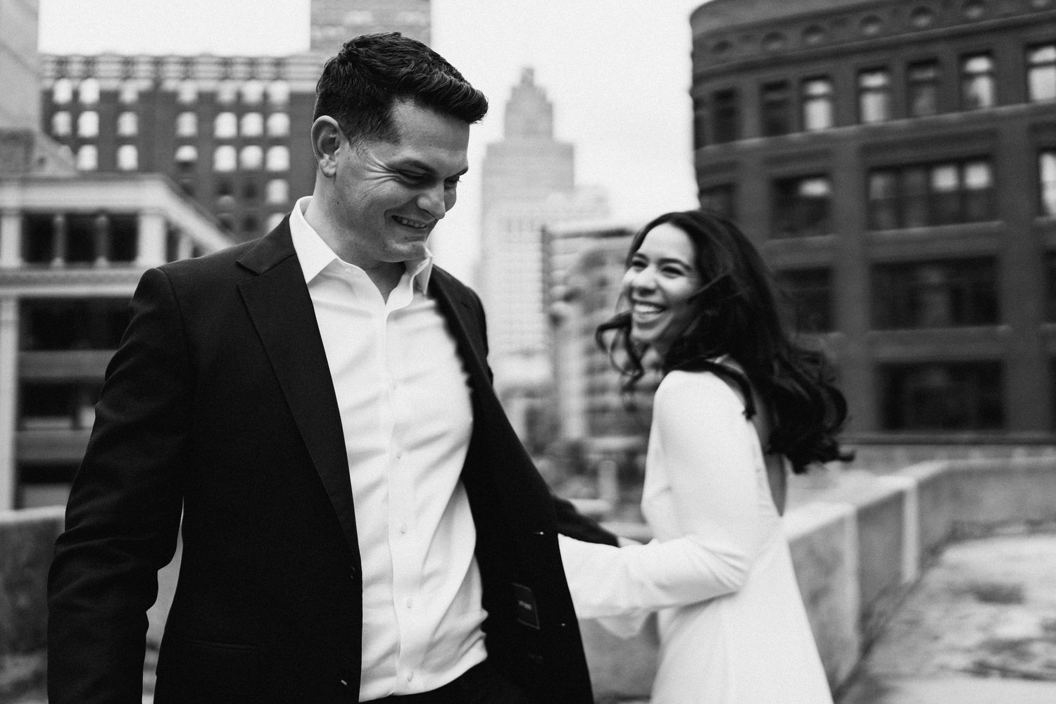 Engaged couple laughing together in an apple orchard during fall session by Bylitos Studio Michigan