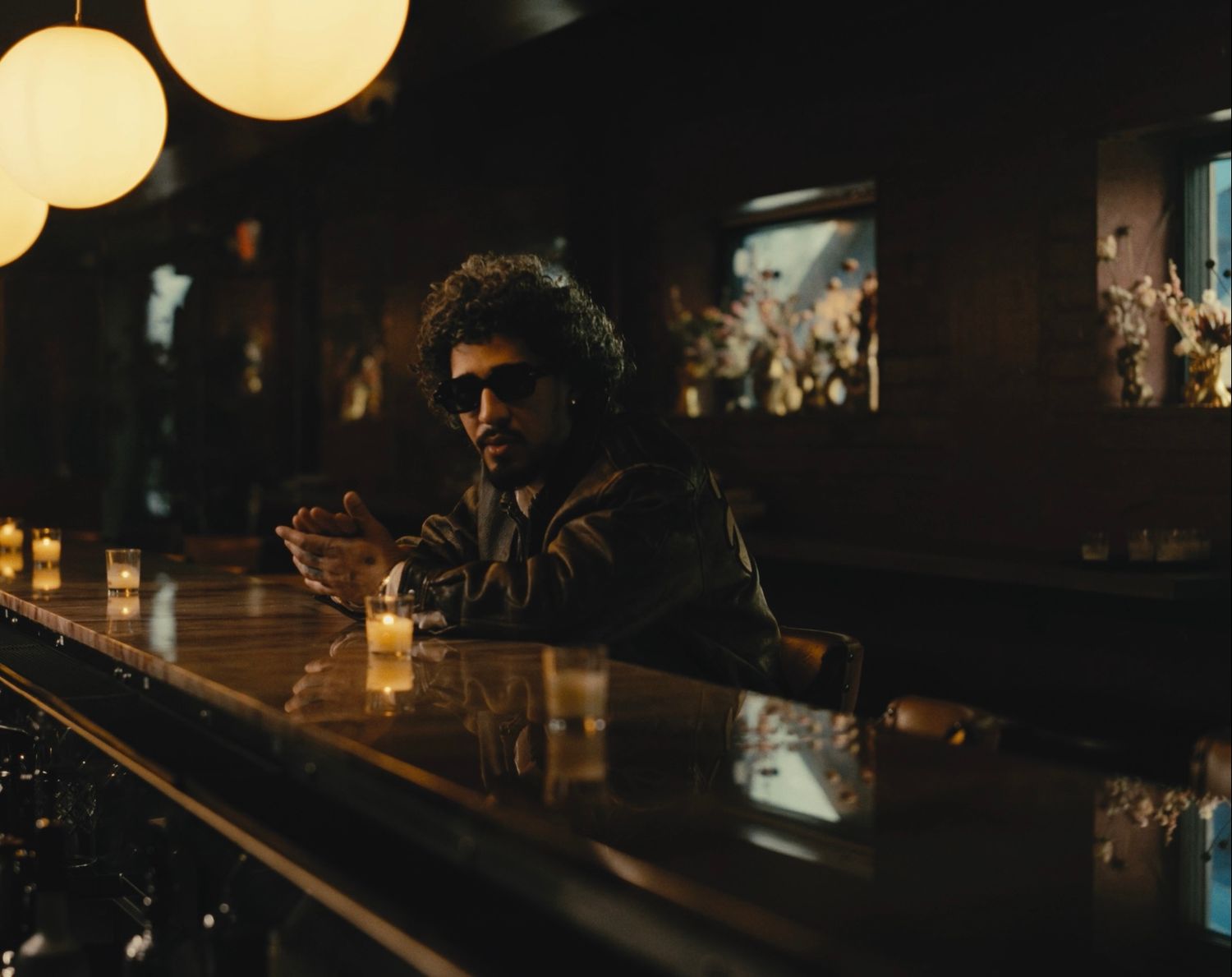 Man in sunglasses sitting at dimly lit bar in cinematic lifestyle shoot by Bylitos Studio Michigan