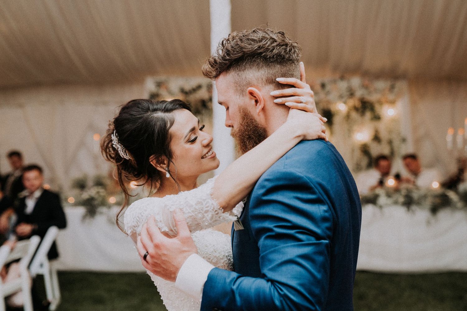 Bride and groom sharing their first dance at an elegant tented Michigan wedding reception by Bylitos Studio