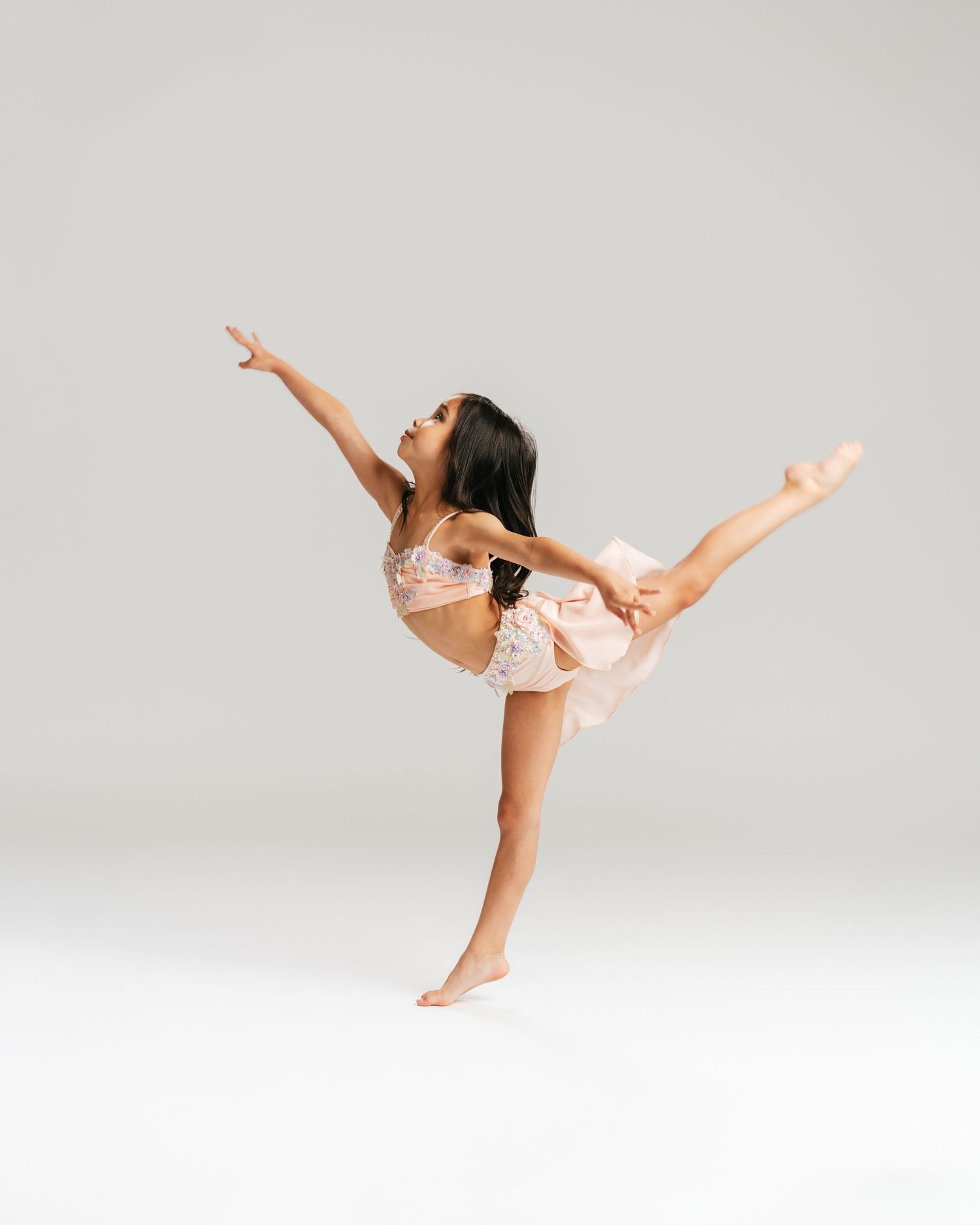 Young dancer in pink leotard doing an arabesque pose in studio editorial by Bylitos Studio Michigan