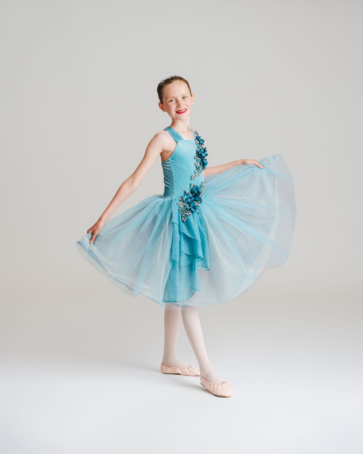 Young ballerina in blue tutu smiling during ballet studio portrait session by Bylitos Studio Michigan