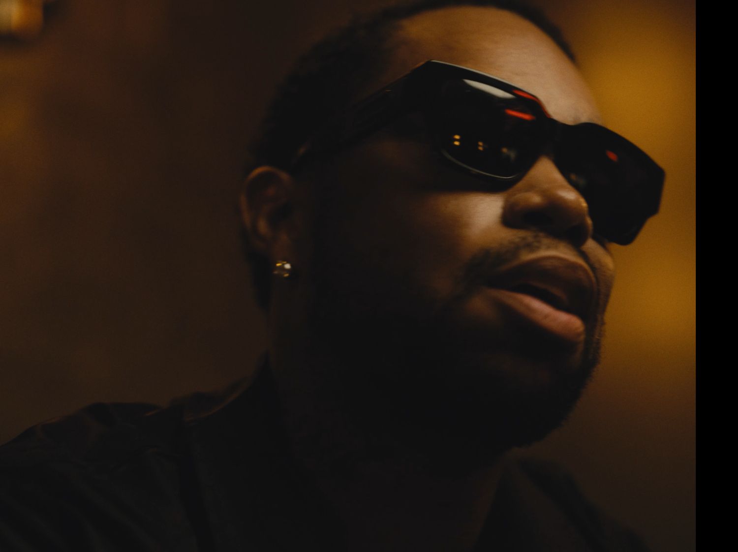 Cinematic close-up portrait of man in bold sunglasses with moody dramatic lighting by Bylitos Studio Michigan