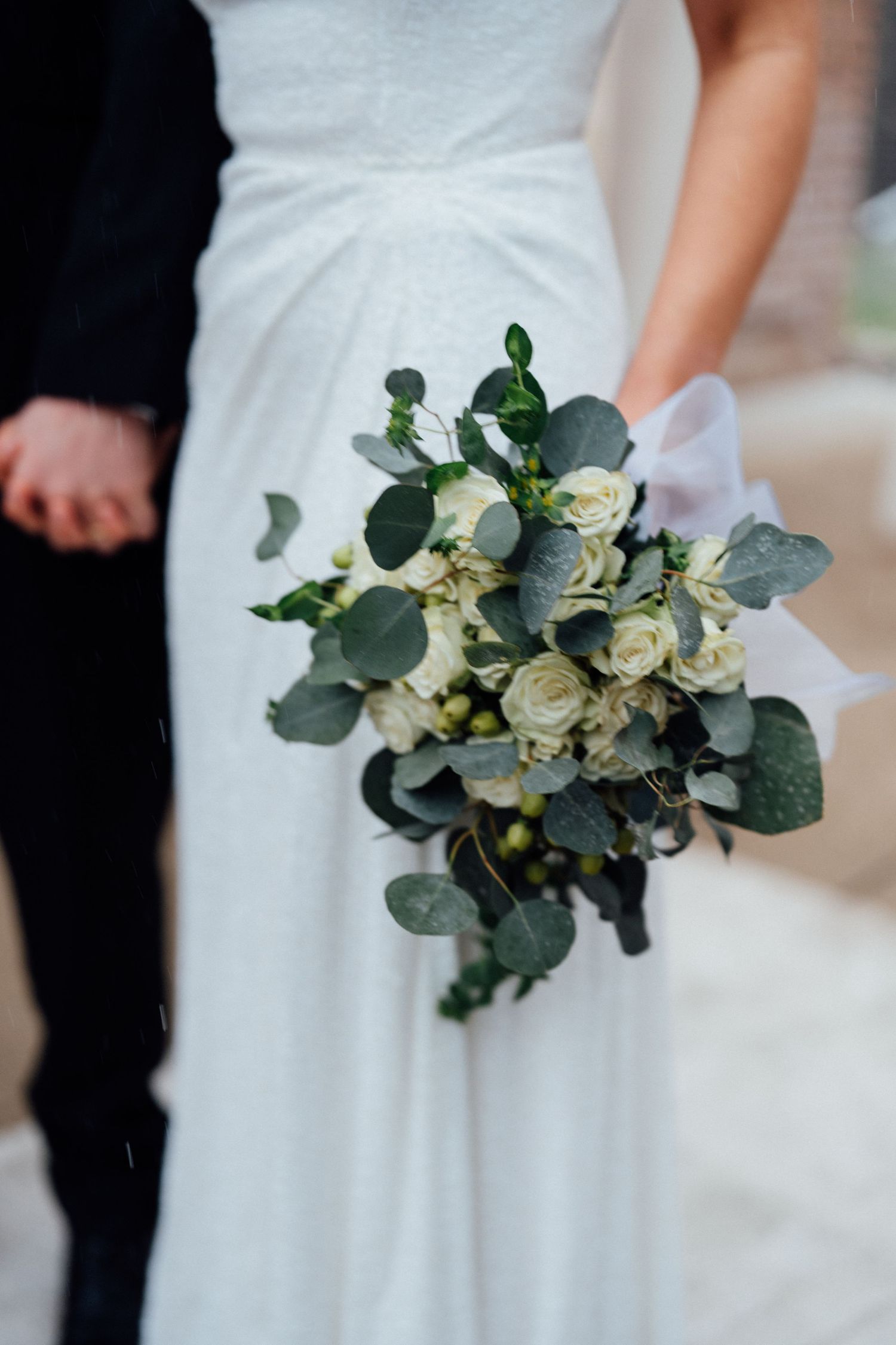 Bride holding lush white rose and eucalyptus bouquet on her wedding day by Bylitos Studio Michigan