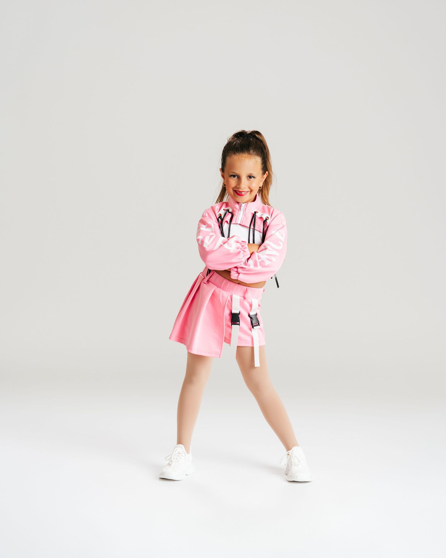 Young dancer in pink costume posing playfully during studio dance editorial by Bylitos Studio Michigan