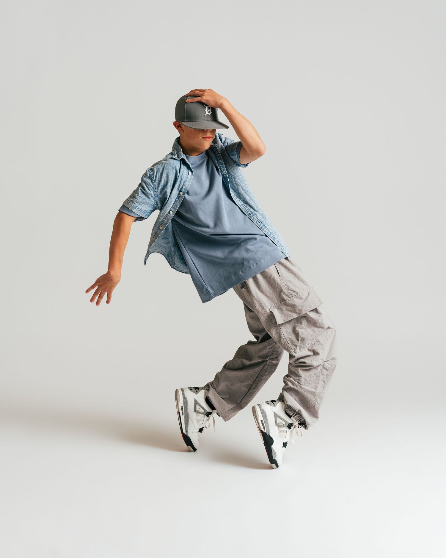 Young male dancer in streetwear mid-move during studio editorial shoot by Bylitos Studio Michigan