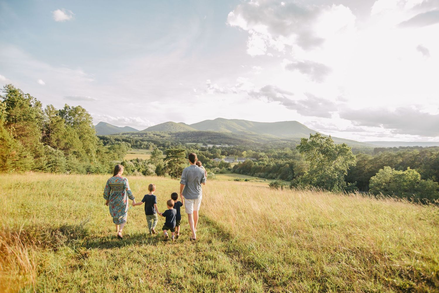 Small group walking along a hilltop meadow with mountain views in the distance.