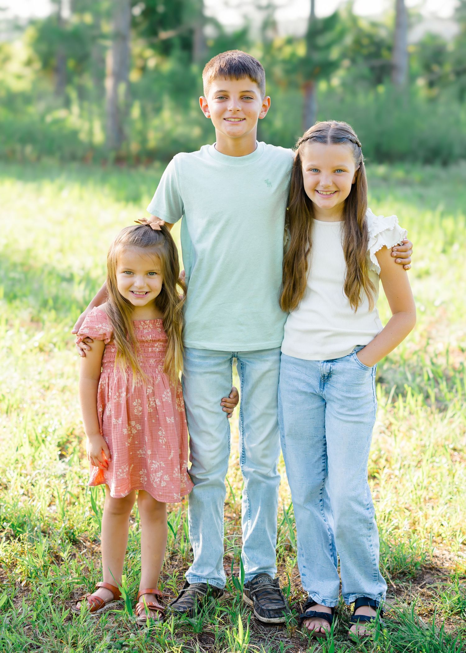 Children and parents pose together in a sunny meadow wearing coordinated casual outfits.