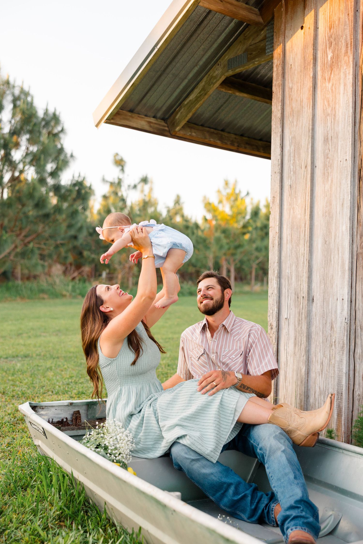 A couple sits together on a covered outdoor porch, playing with their baby in a joyful candid moment.