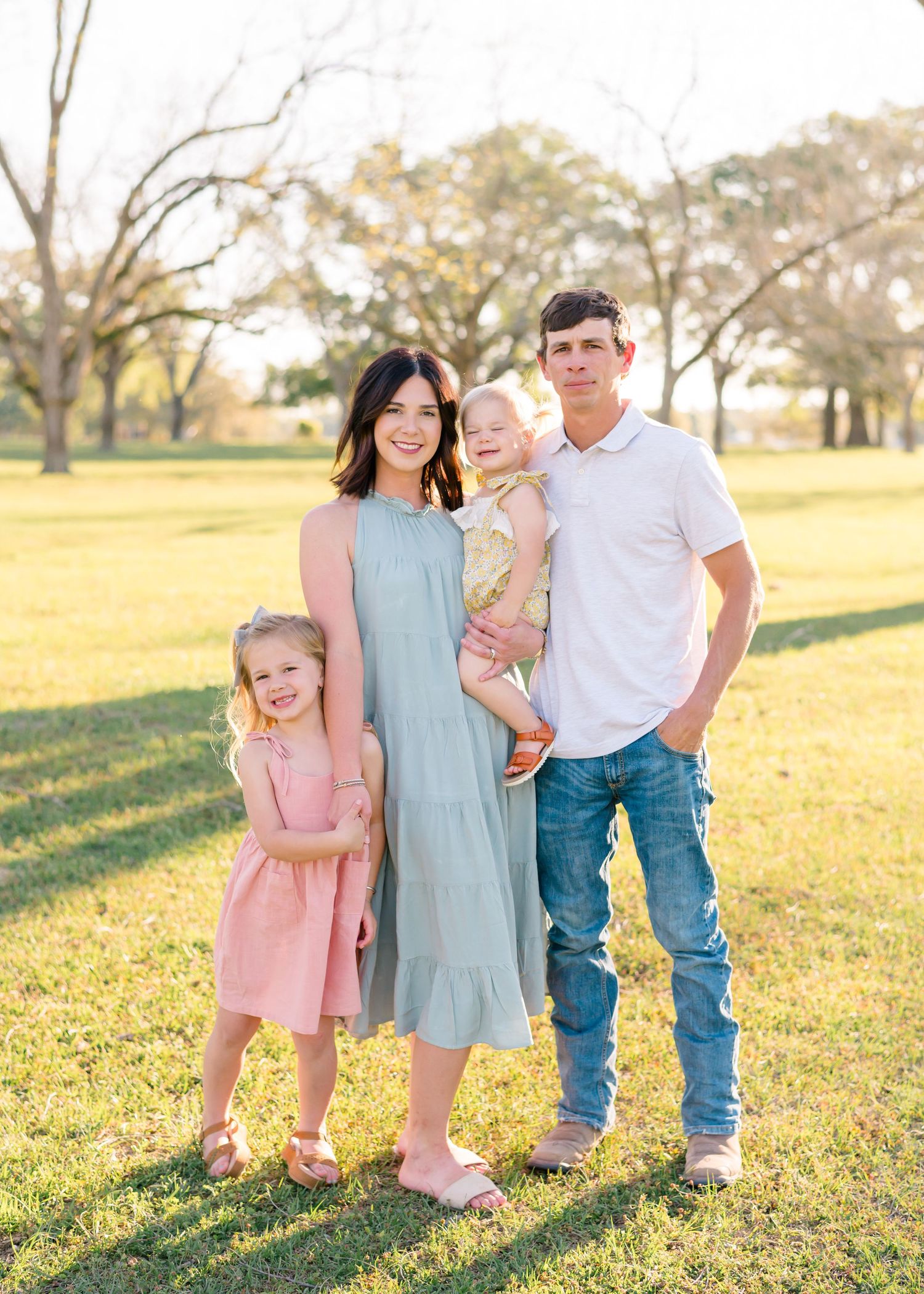 Family group portraits taken in a sunny field at golden hour.
