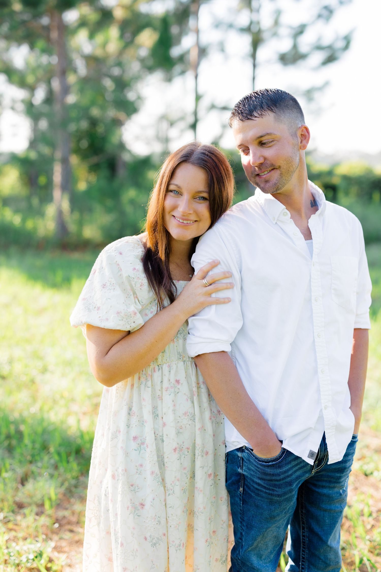 Couple in white and cream colored outfits share intimate moments in a sunny outdoor setting.