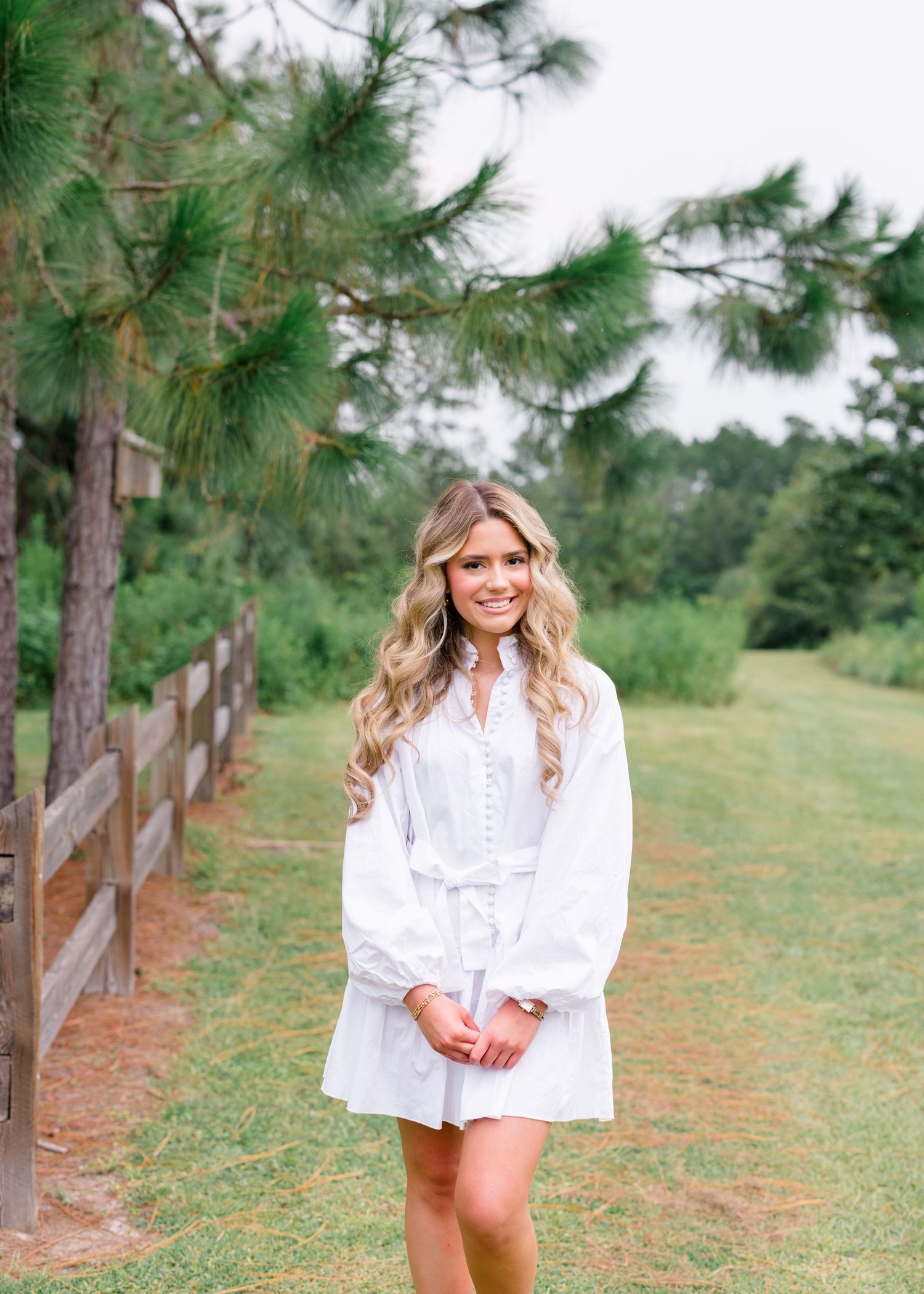 Outdoor photo session in a pine forest with person wearing flowing white dress.