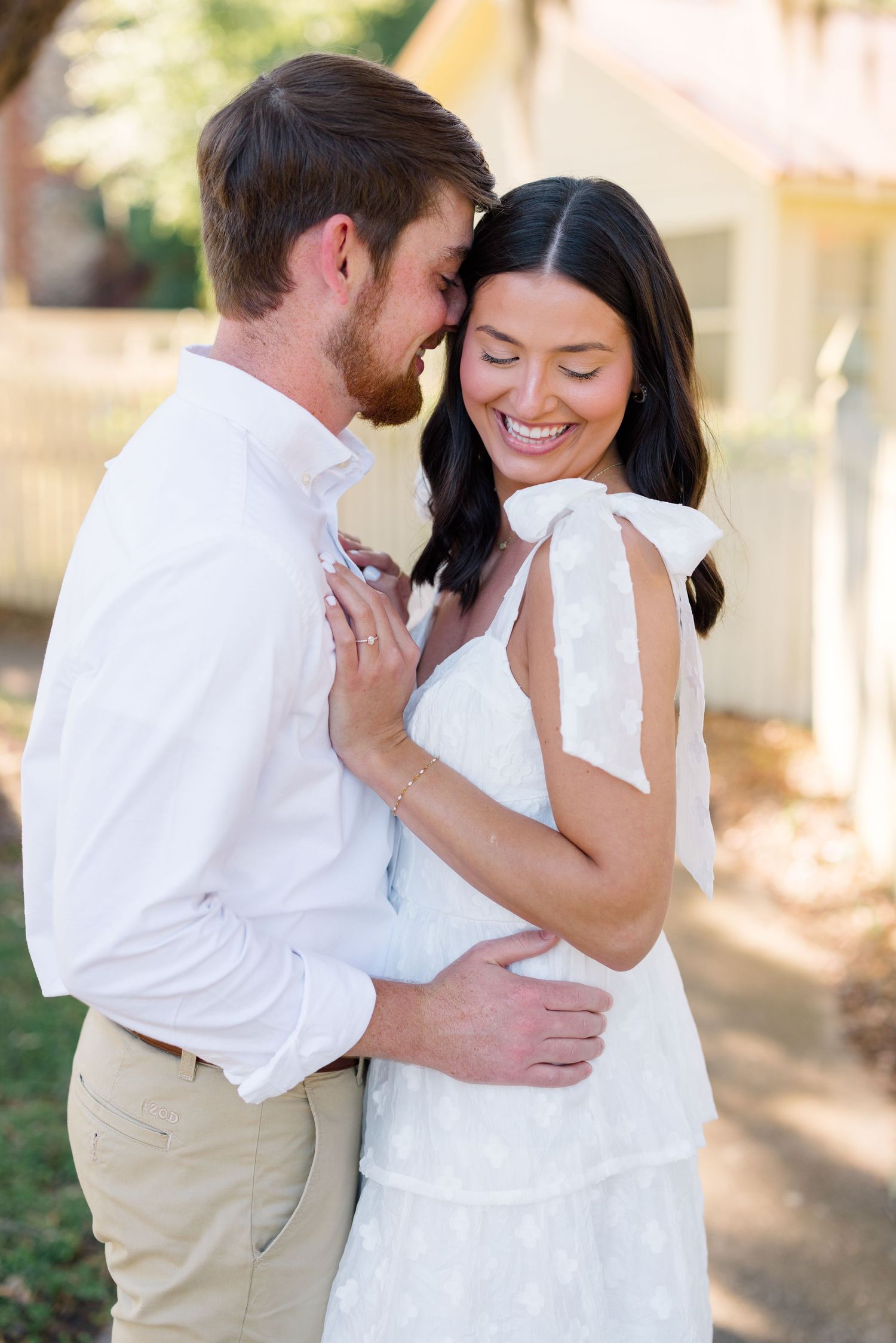 A couple shares a tender moment while dressed in coordinated white outfits.