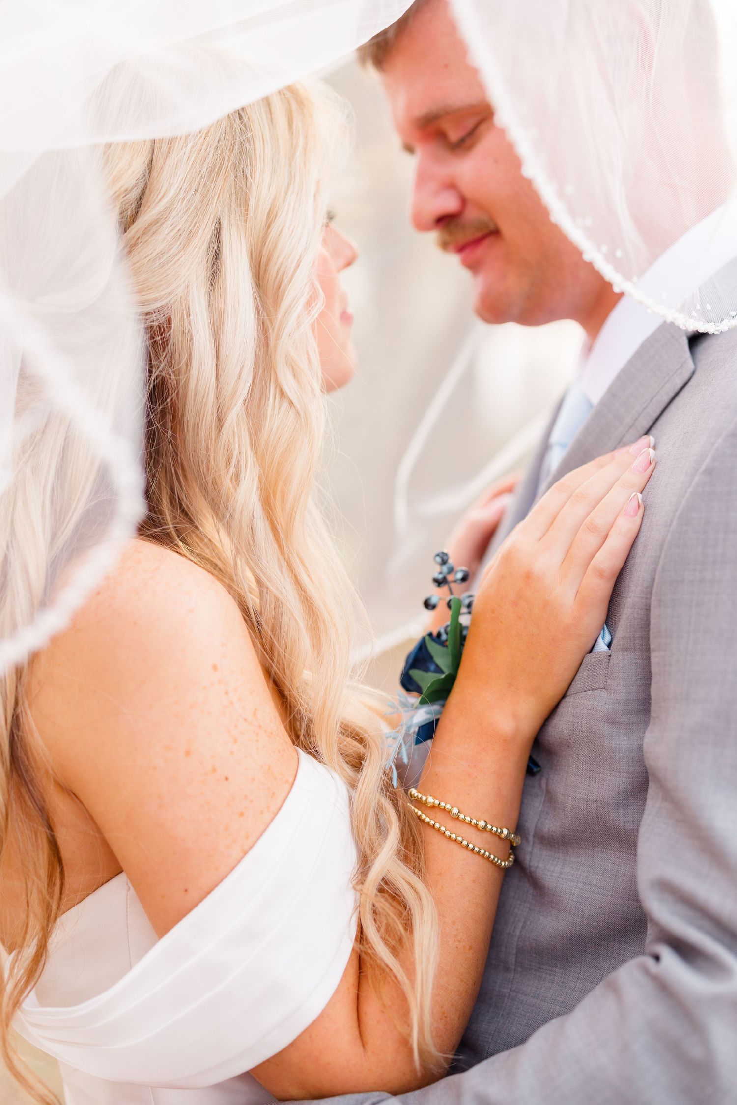 Close-up romantic wedding photos showing tender moments between bride in white dress and groom in gray suit.