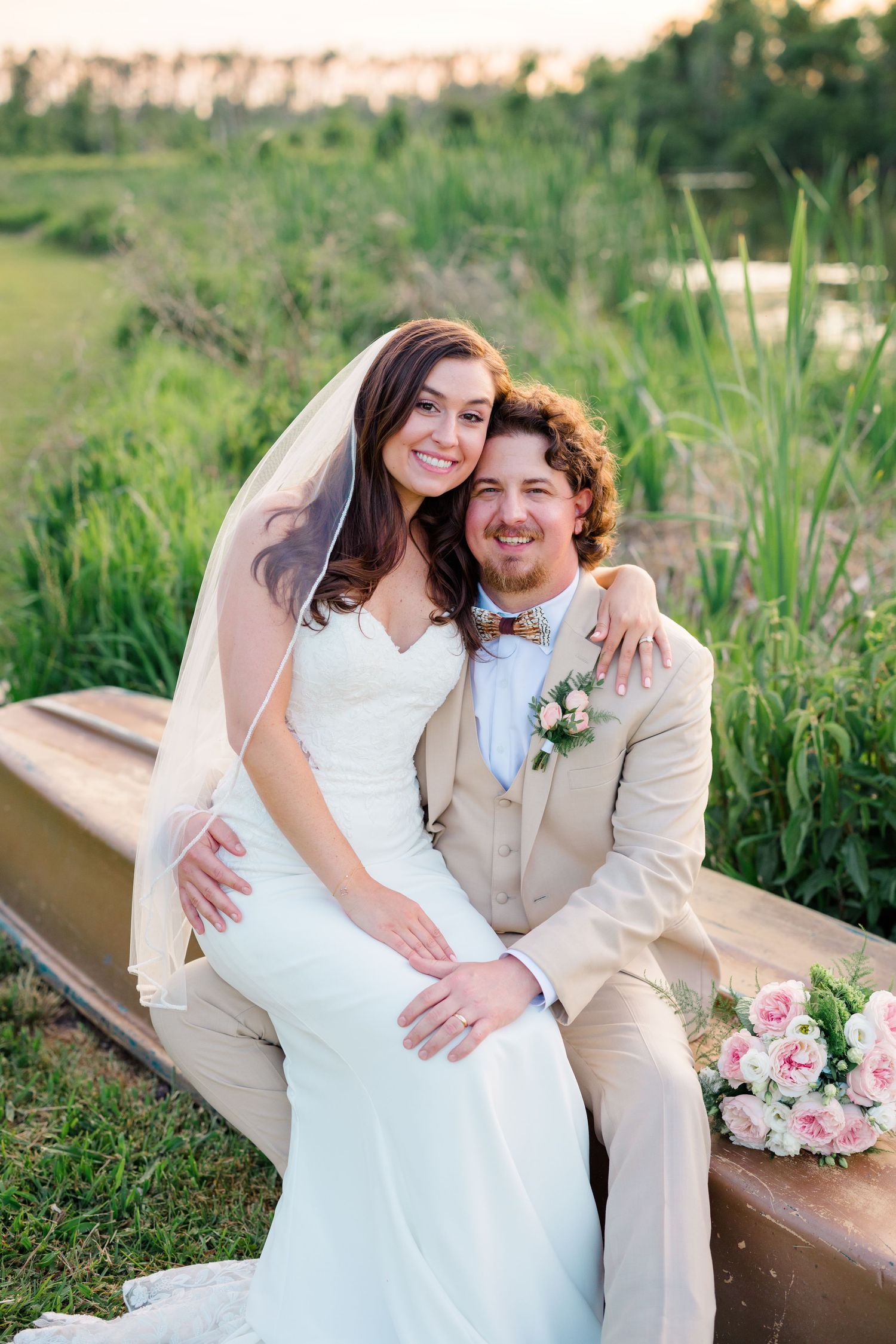 A romantic outdoor wedding portrait on a rustic bench at sunset.