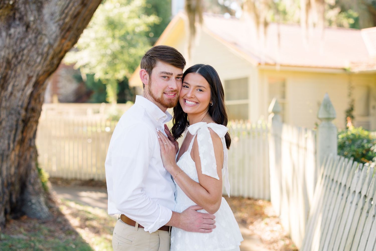 A couple poses for an engagement photo in white and khaki clothing.