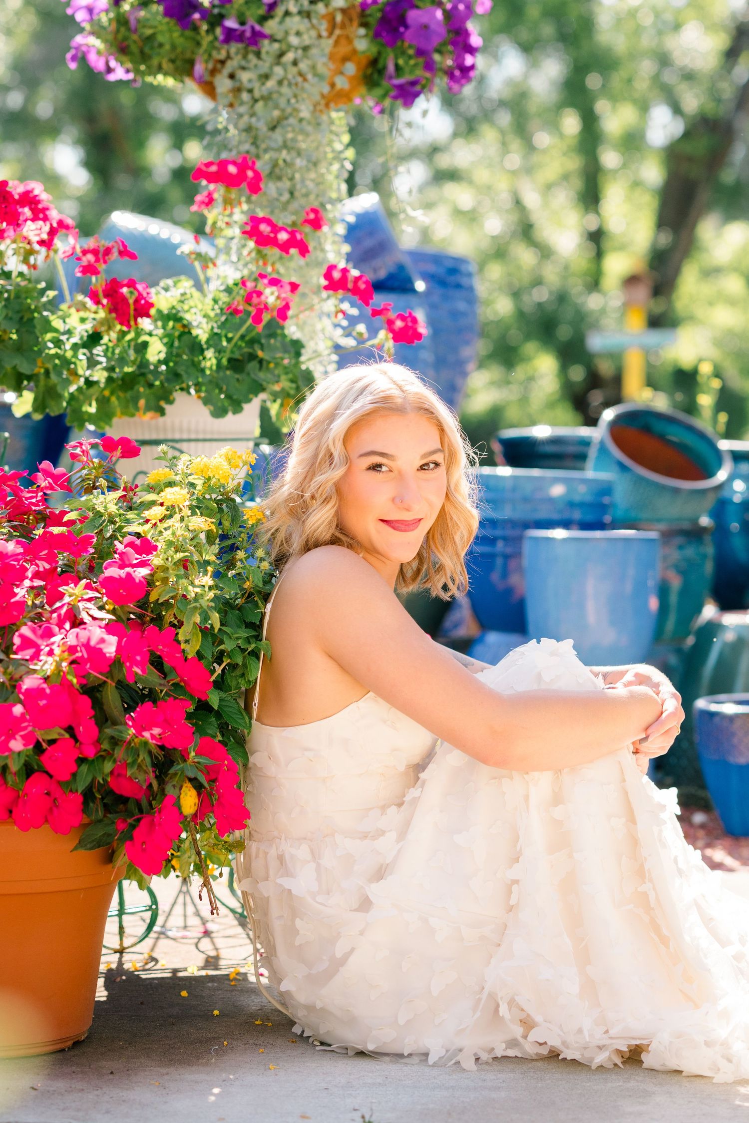 Portrait with vibrant pink flowers and blue planters on a sunny garden patio.