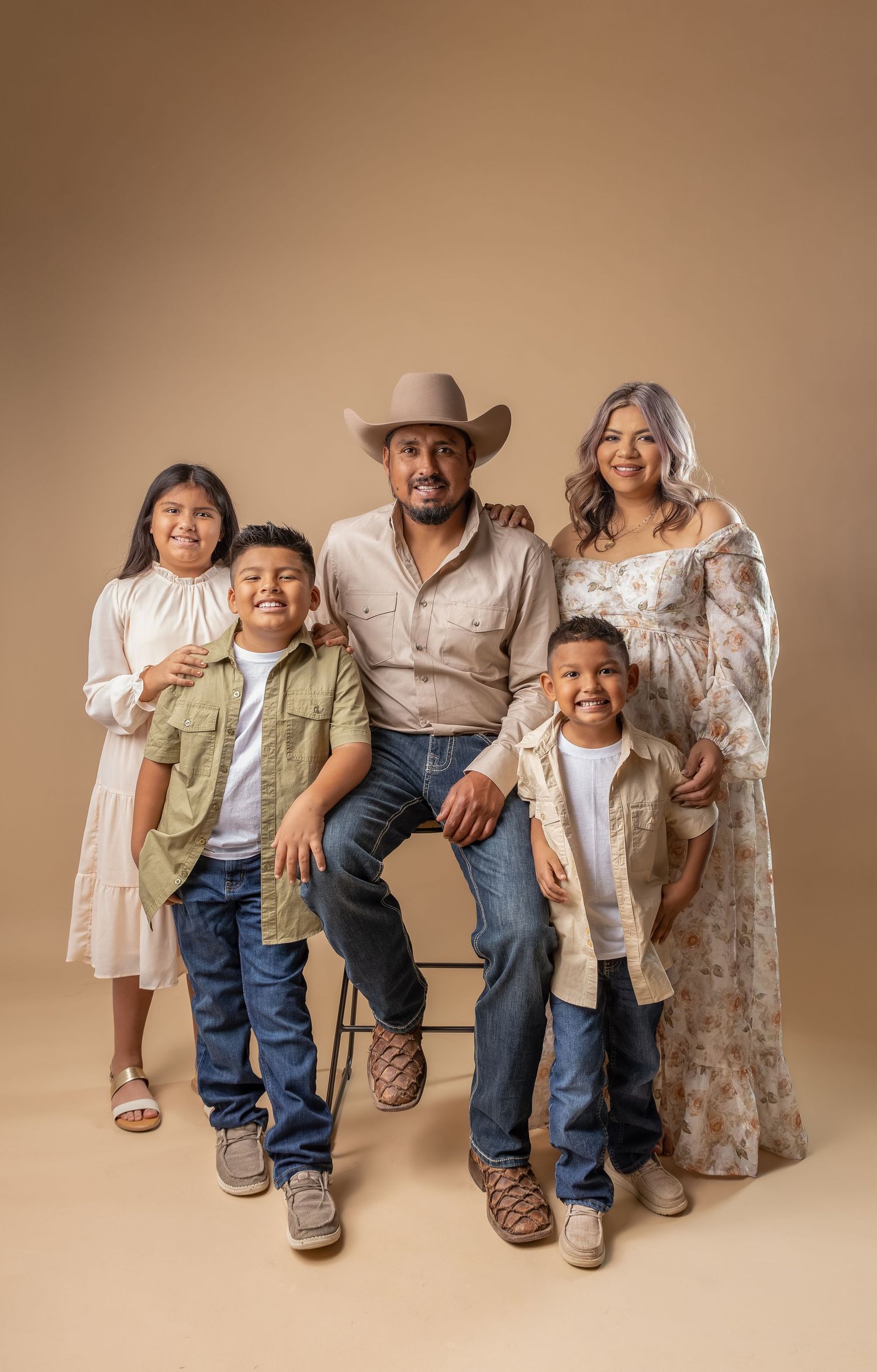 Family portrait series showing parents and children sitting together against neutral backdrop in coordinated casual outfits.