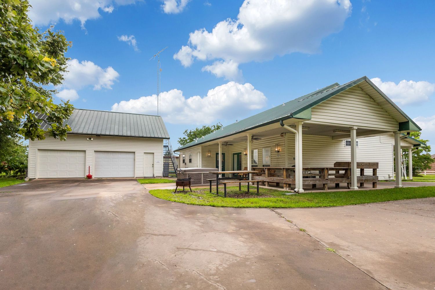 Panoramic view of a modern agricultural facility with multiple connected buildings under a bright blue sky with white clouds.
