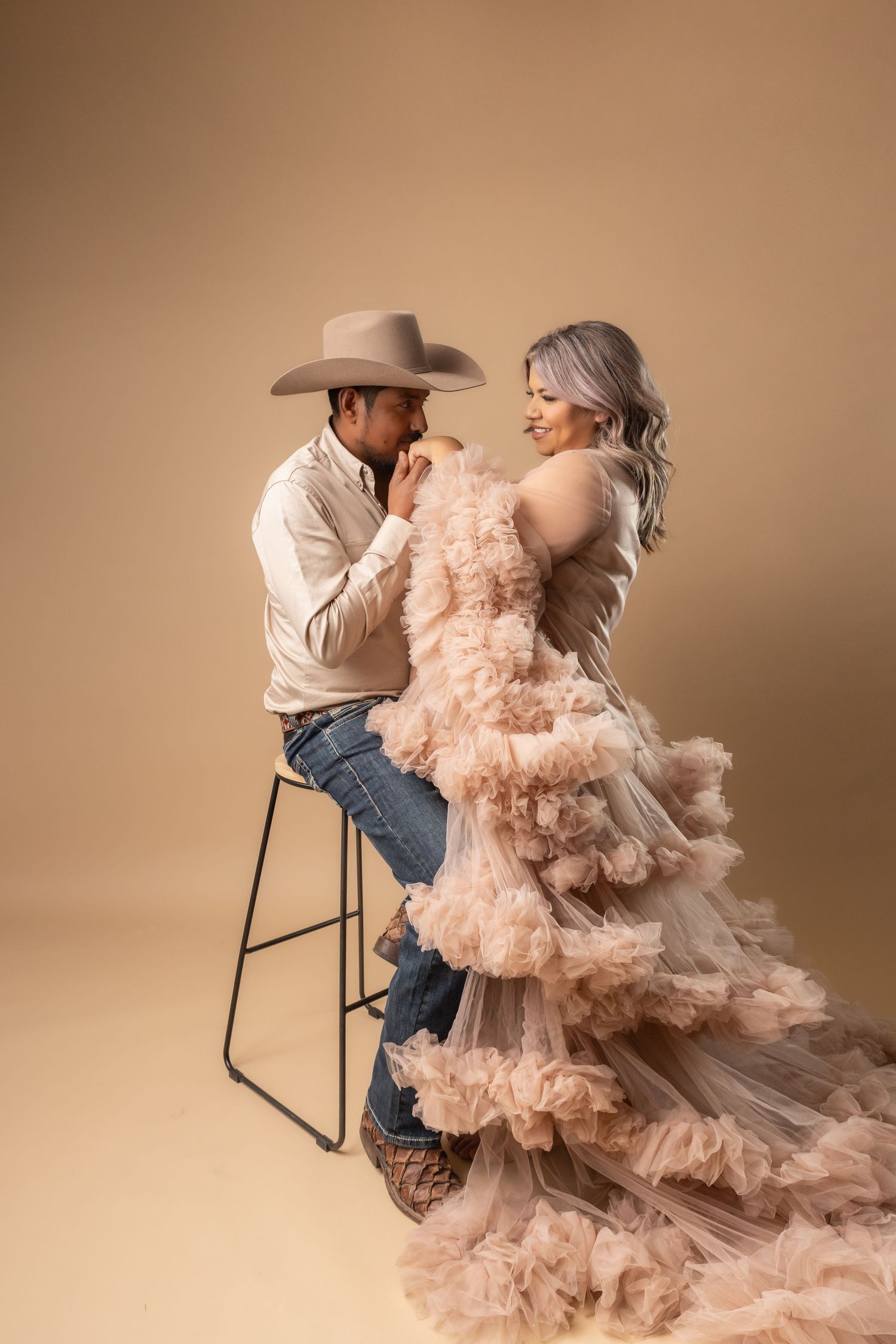 A romantic couple in western and formal attire share intimate poses in a soft peach-toned studio photo sequence.