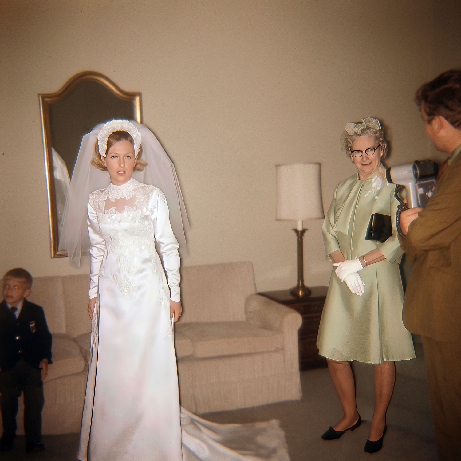Vintage 1960s wedding photo showing bride in white gown with veil, older woman in green dress, and child in suit indoors.