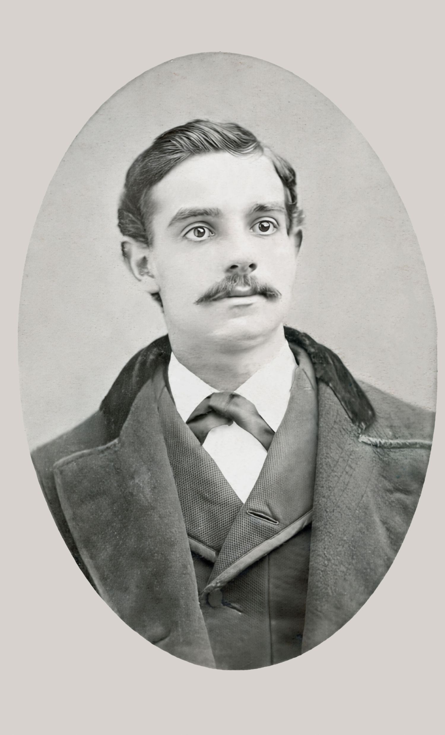 Vintage oval portrait of a young Victorian-era man with a mustache, wearing a suit and tie, black and white photo.